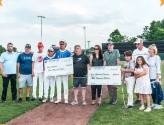 Families and players holding donation checks on the field