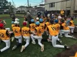 Youth team in gold jerseys huddled on the field