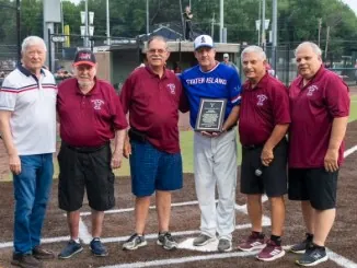 Honorees in maroon shirts with a plaque recipient